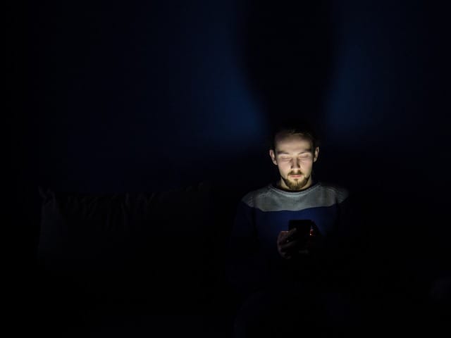 man using cell phone in dark